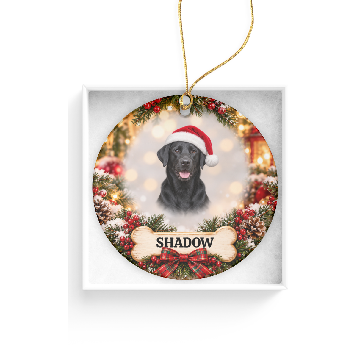 Personalized black Labrador Christmas ornament featuring a Santa hat, festive greenery and a printed bone-shaped nameplate reading Shadow